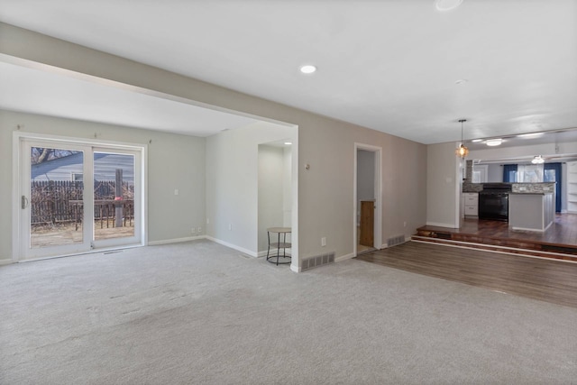 unfurnished living room featuring carpet, visible vents, and baseboards