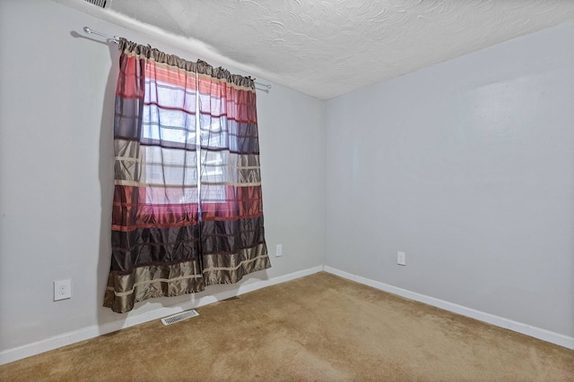 carpeted spare room with visible vents, a textured ceiling, and baseboards