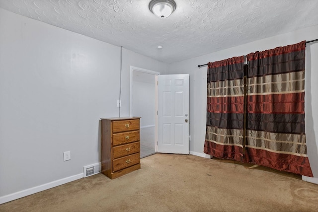 bedroom with a textured ceiling, carpet floors, visible vents, and baseboards