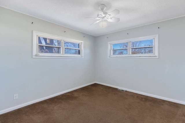 unfurnished room with plenty of natural light, a textured ceiling, dark carpet, and baseboards