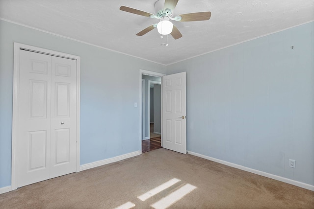 unfurnished bedroom featuring baseboards, a closet, carpet, and crown molding