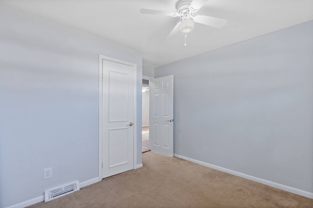 carpeted spare room with baseboards, visible vents, and ceiling fan