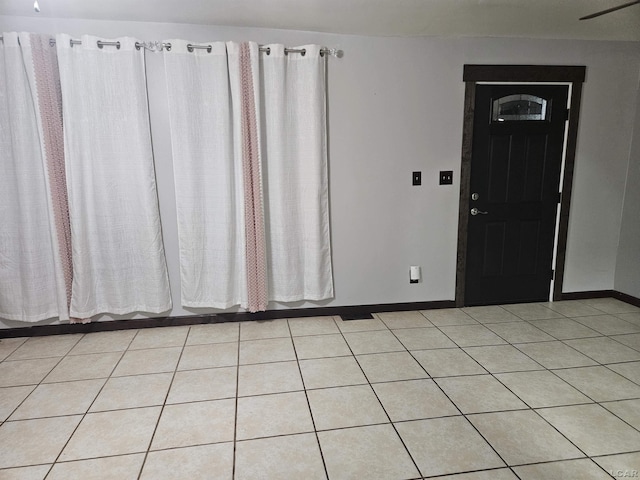 empty room featuring baseboards and light tile patterned floors