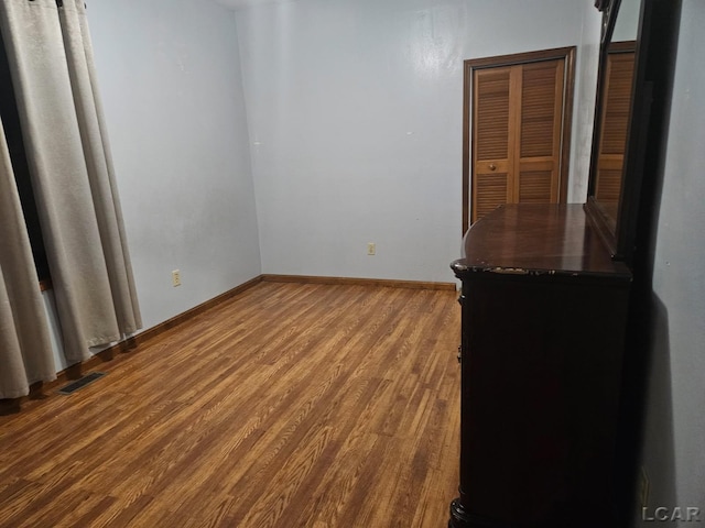 spare room with baseboards, visible vents, and wood finished floors