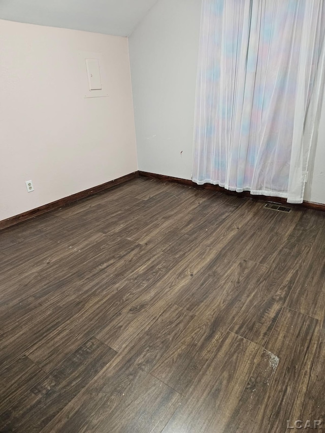 empty room featuring dark wood-style floors, visible vents, and baseboards