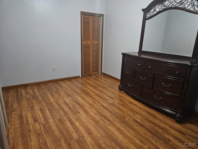 unfurnished bedroom with a closet, baseboards, and wood finished floors