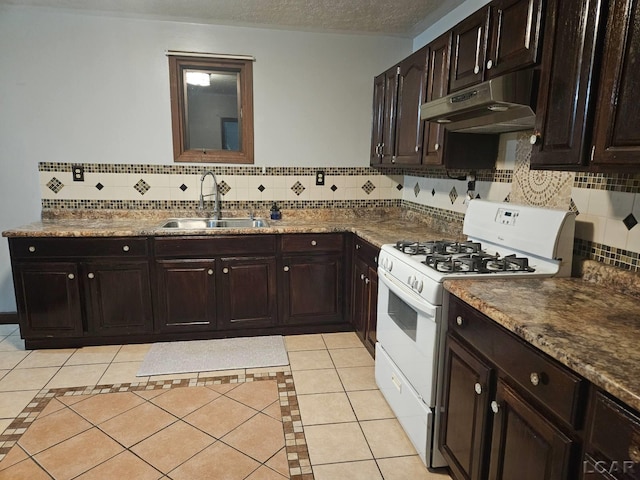 kitchen with light tile patterned floors, a sink, a textured ceiling, under cabinet range hood, and white gas range oven