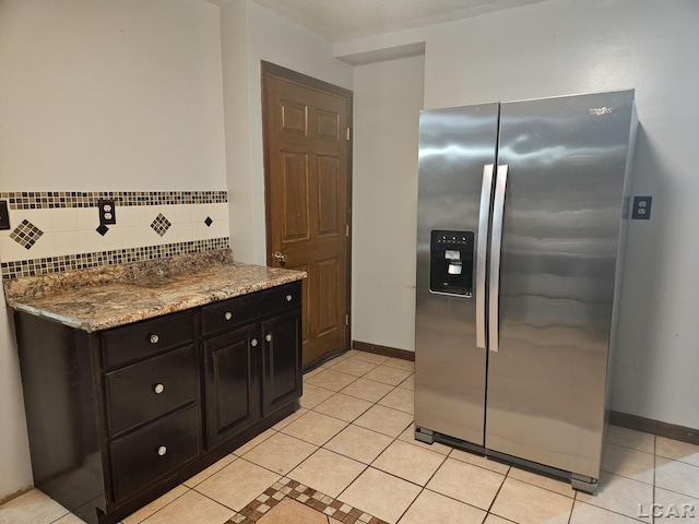 kitchen with light tile patterned floors, stone countertops, decorative backsplash, and stainless steel fridge with ice dispenser