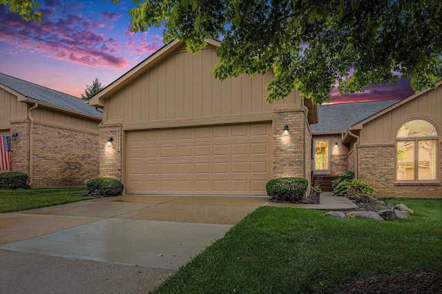 view of front facade featuring driveway, a garage, a lawn, and brick siding