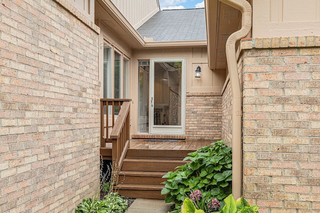 property entrance with roof with shingles and brick siding