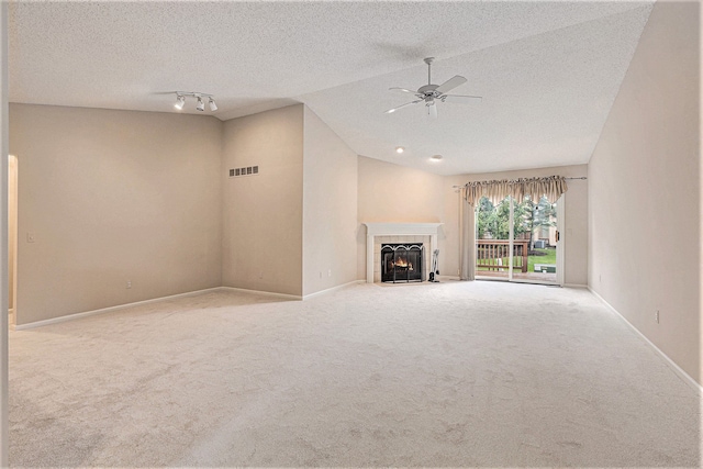 unfurnished living room featuring lofted ceiling, visible vents, a tiled fireplace, light carpet, and a textured ceiling