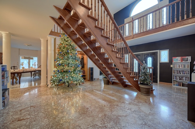 entrance foyer with marble finish floor, decorative columns, a high ceiling, and stairs