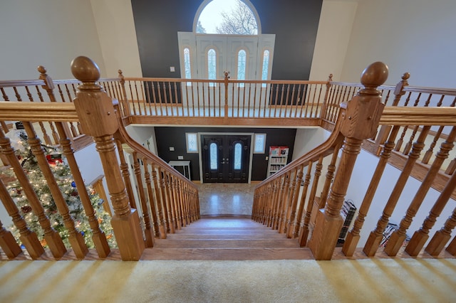 stairway featuring a towering ceiling and wood finished floors