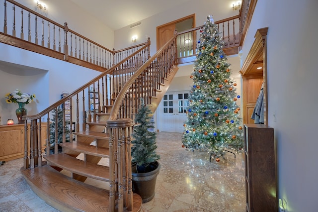 stairway featuring visible vents and a high ceiling