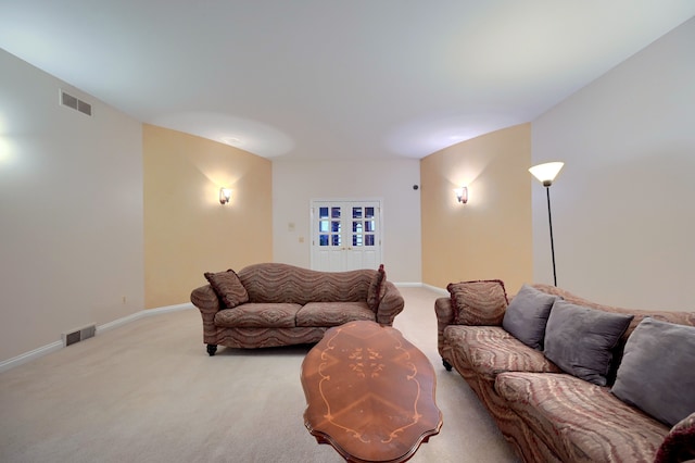 living area with baseboards, visible vents, and light colored carpet