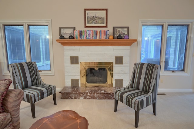 sitting room with visible vents, a stone fireplace, and light colored carpet