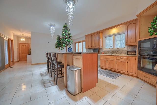 kitchen featuring tasteful backsplash, stone countertops, a kitchen island, black appliances, and a kitchen bar