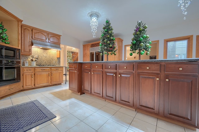 kitchen with light tile patterned floors, decorative backsplash, brown cabinets, under cabinet range hood, and black appliances