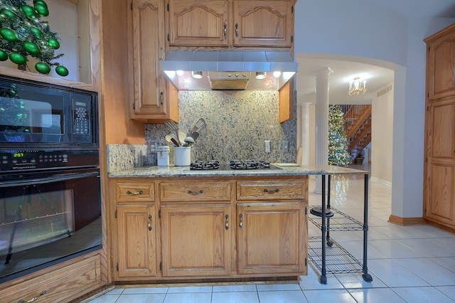 kitchen with tasteful backsplash, ornate columns, range hood, black appliances, and a kitchen bar