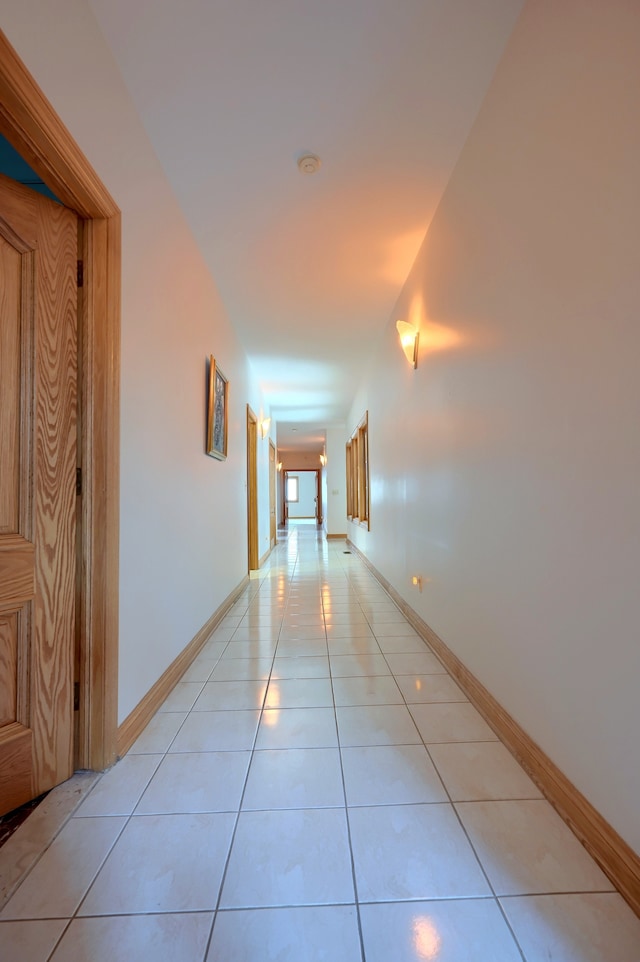 corridor featuring light tile patterned flooring and baseboards