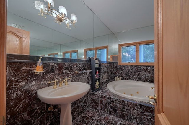 bathroom featuring a whirlpool tub, plenty of natural light, a chandelier, and visible vents