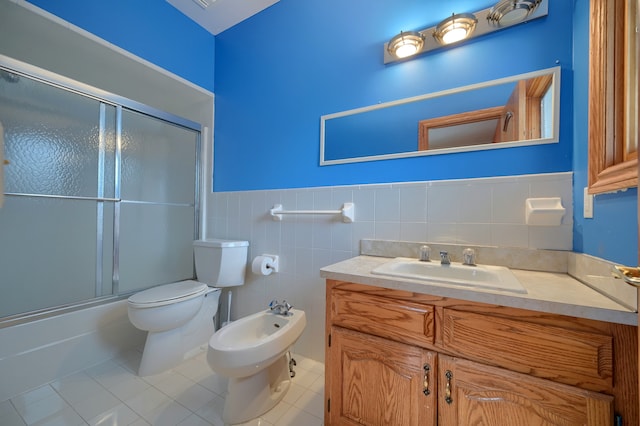 full bath with wainscoting, toilet, tile patterned flooring, a bidet, and tile walls