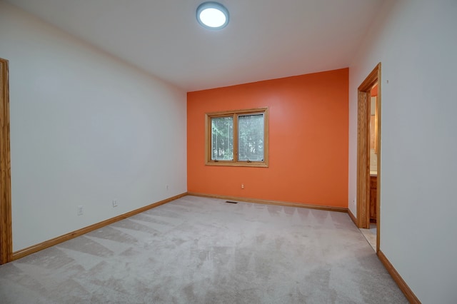 spare room featuring light carpet, visible vents, and baseboards