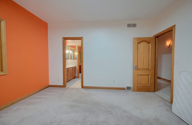 bedroom with light carpet, baseboards, visible vents, and ensuite bathroom