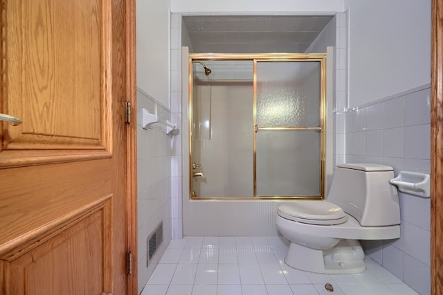 bathroom featuring enclosed tub / shower combo, toilet, visible vents, tile walls, and tile patterned floors