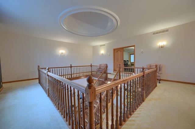 corridor featuring baseboards, an upstairs landing, visible vents, and light colored carpet