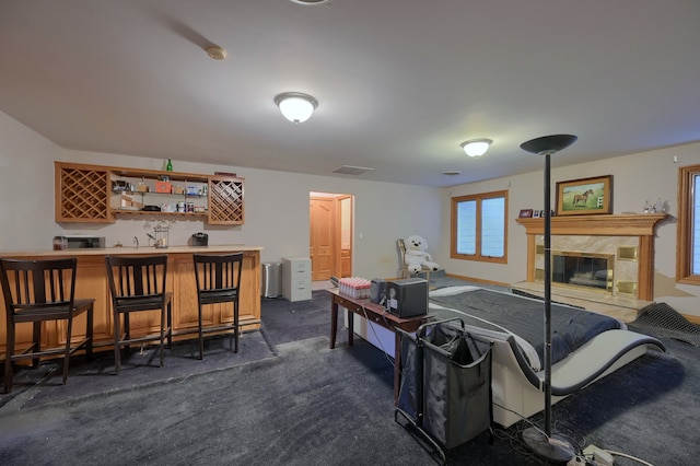 living area with wet bar, visible vents, dark colored carpet, and a premium fireplace