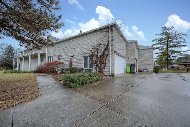 view of home's exterior with a garage, stone siding, and concrete driveway