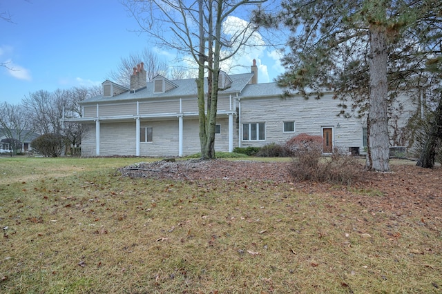 view of front of house featuring stone siding, a chimney, and a front yard