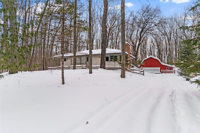 yard layered in snow with an outbuilding, covered porch, a detached garage, and a barn