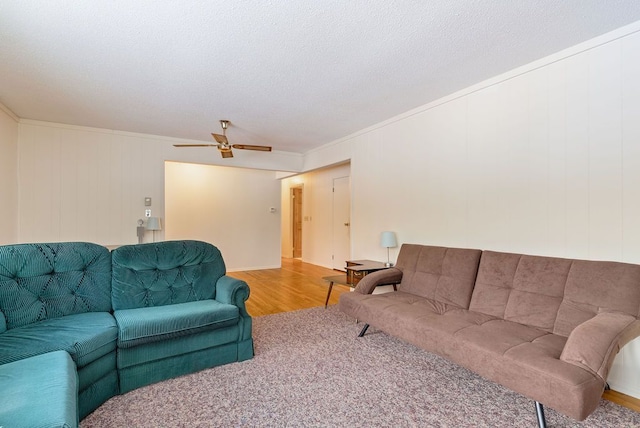 living area with ornamental molding, ceiling fan, a textured ceiling, and wood finished floors