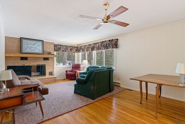 living area with a textured ceiling, wood-type flooring, a fireplace, and a baseboard radiator