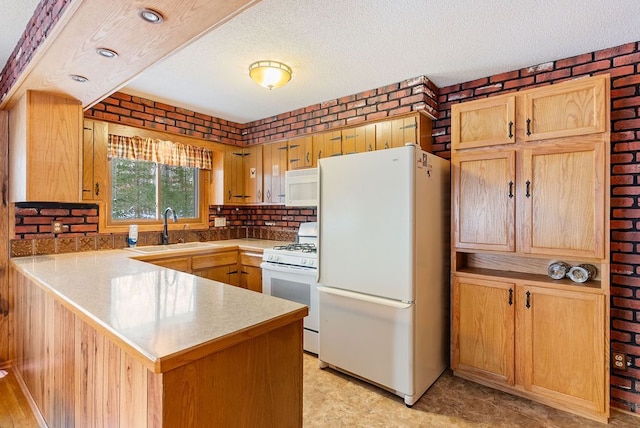 kitchen with brick wall, a peninsula, white appliances, a sink, and light countertops