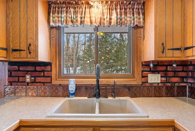 kitchen with brown cabinetry, light countertops, and a sink