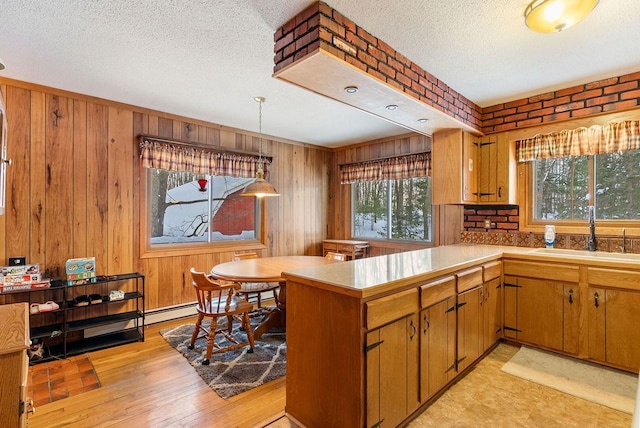 kitchen with a peninsula, a sink, light countertops, and brown cabinets