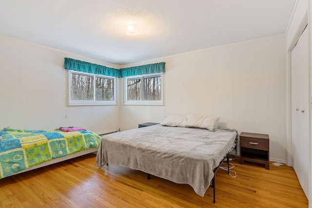 bedroom with a closet, baseboard heating, and wood finished floors