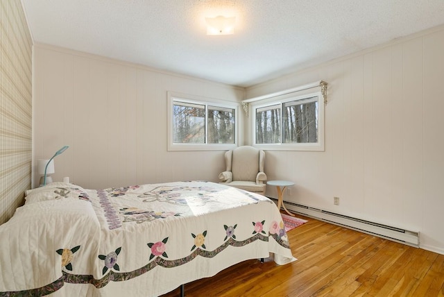 bedroom featuring hardwood / wood-style flooring, baseboard heating, and a textured ceiling