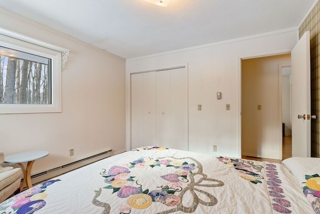 bedroom with ornamental molding, baseboard heating, and a closet