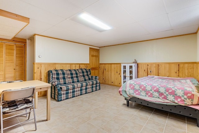 bedroom featuring a paneled ceiling, wood walls, and wainscoting