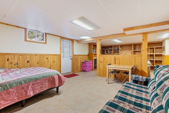 bedroom with a paneled ceiling, wooden walls, and wainscoting