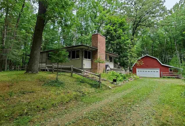 view of front facade with a detached garage, fence, an outdoor structure, a front lawn, and a chimney