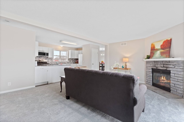 living room with visible vents, a fireplace, light carpet, and baseboards