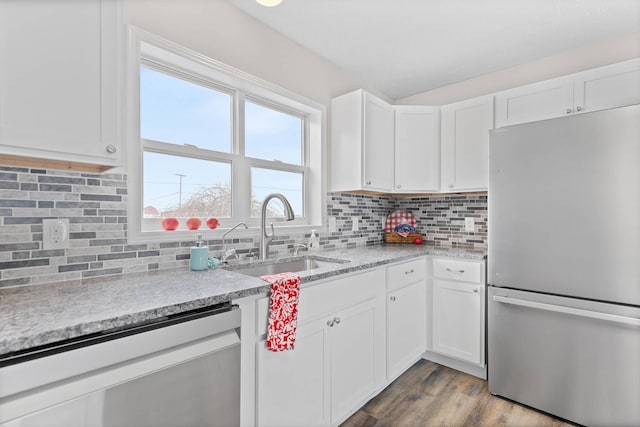 kitchen with decorative backsplash, appliances with stainless steel finishes, white cabinets, a sink, and wood finished floors