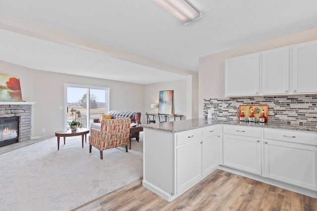 kitchen with white cabinets, light stone countertops, a fireplace, and open floor plan