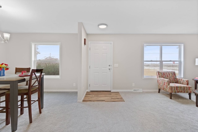 entrance foyer with carpet flooring, visible vents, baseboards, and an inviting chandelier