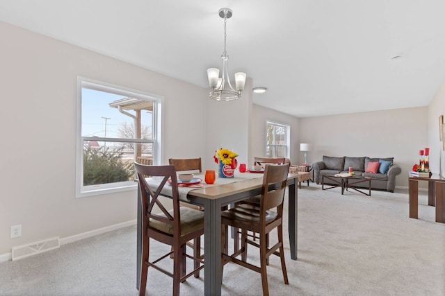 dining area with visible vents, a notable chandelier, light carpet, and baseboards